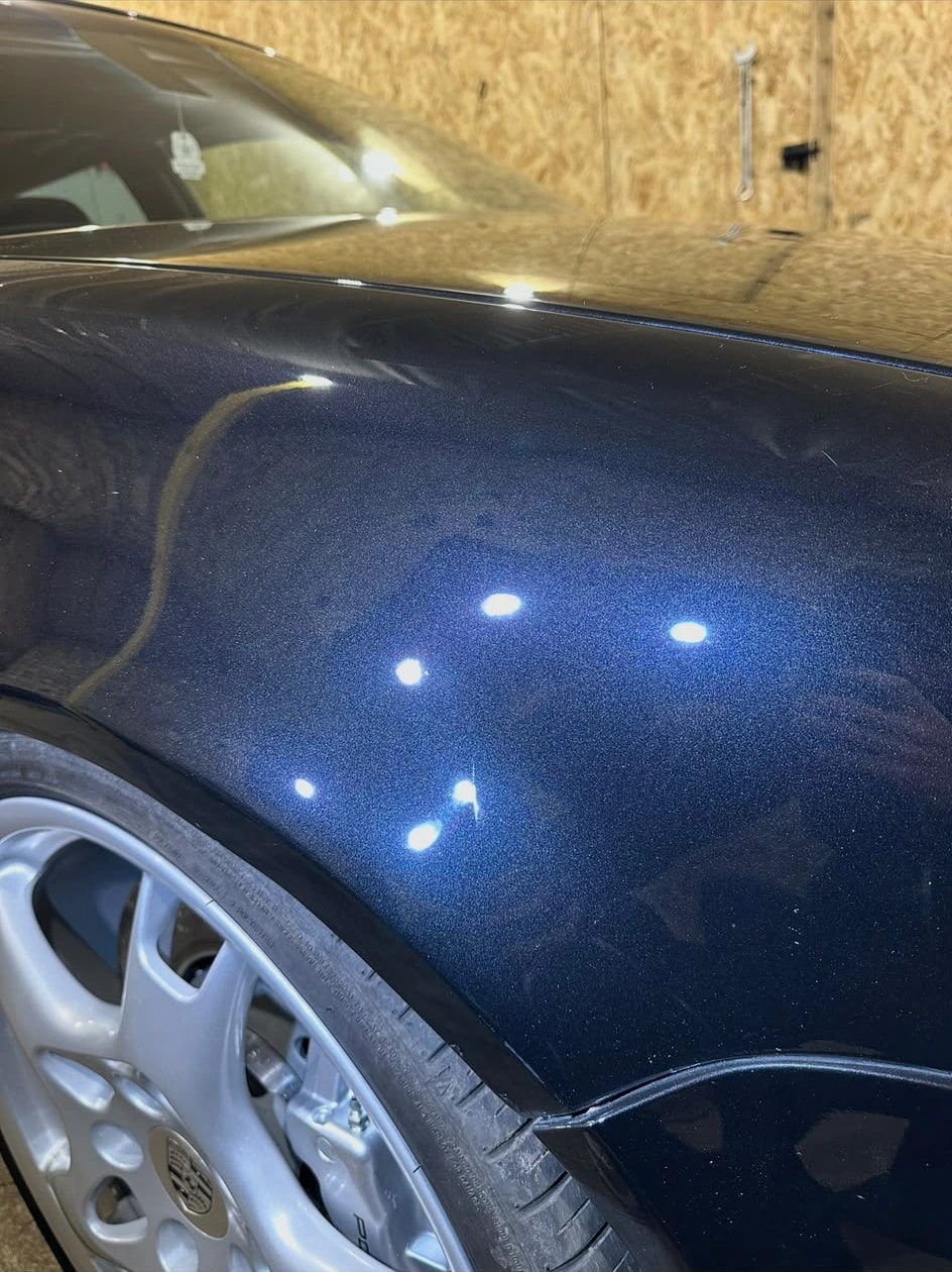 Avant : aile avant gauche bleue d’une Volkswagen Golf 4 R32 sous la lampe, vernis marqué
