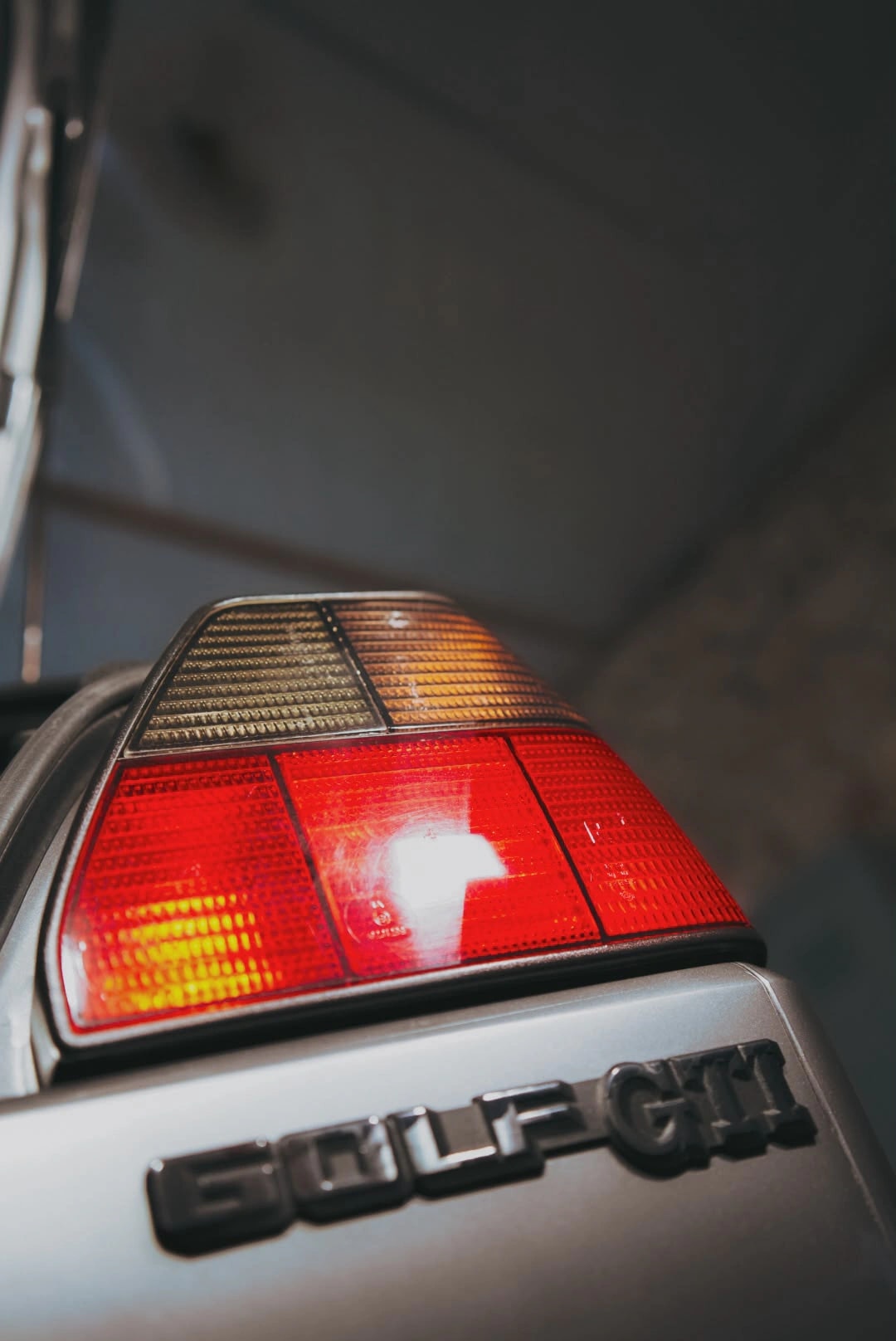 Feu arrière et badge GOLF GTI d’une Golf 2 GTI après lavage, sous la lumière de l’atelier