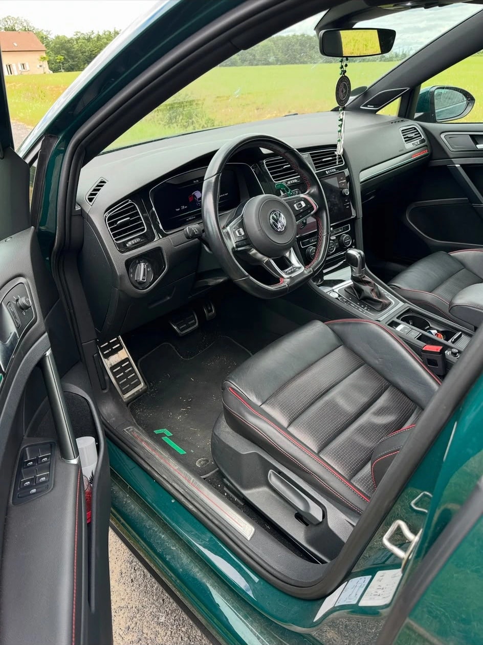 Intérieur cuir noir à surpiqûres rouges d’une Golf 7 verte, portière ouverte sur la campagne