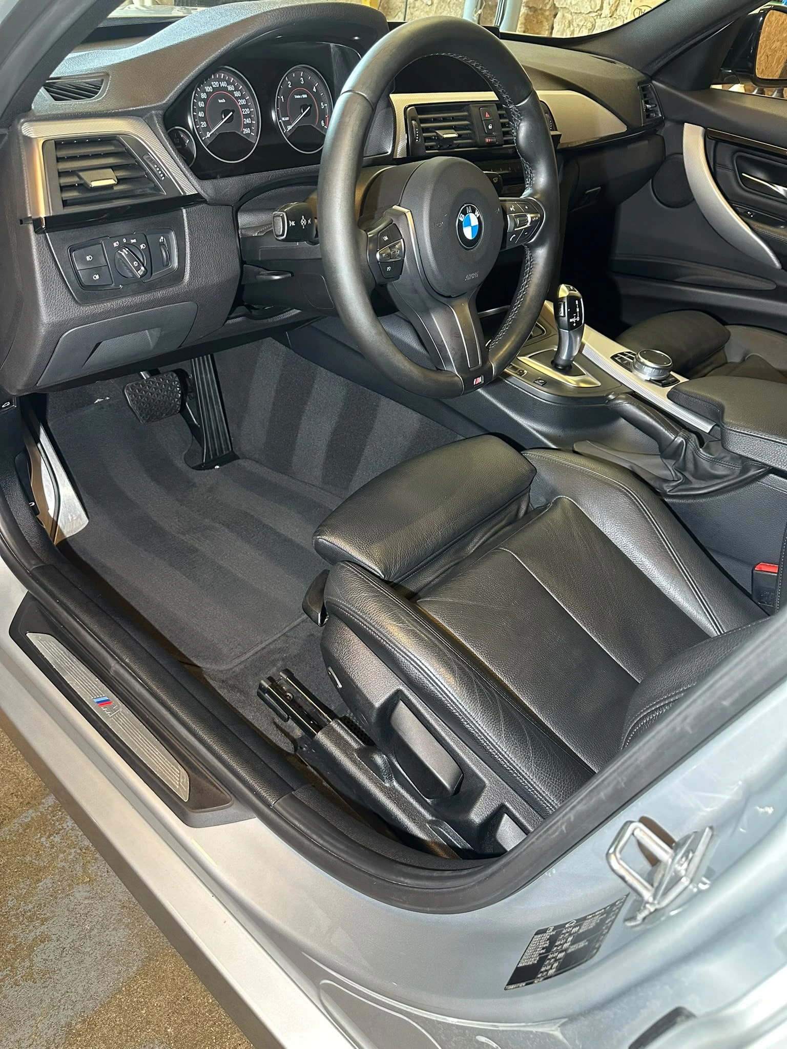 Intérieur cuir noir d’une BMW Série 3 Break après nettoyage, porte conducteur ouverte