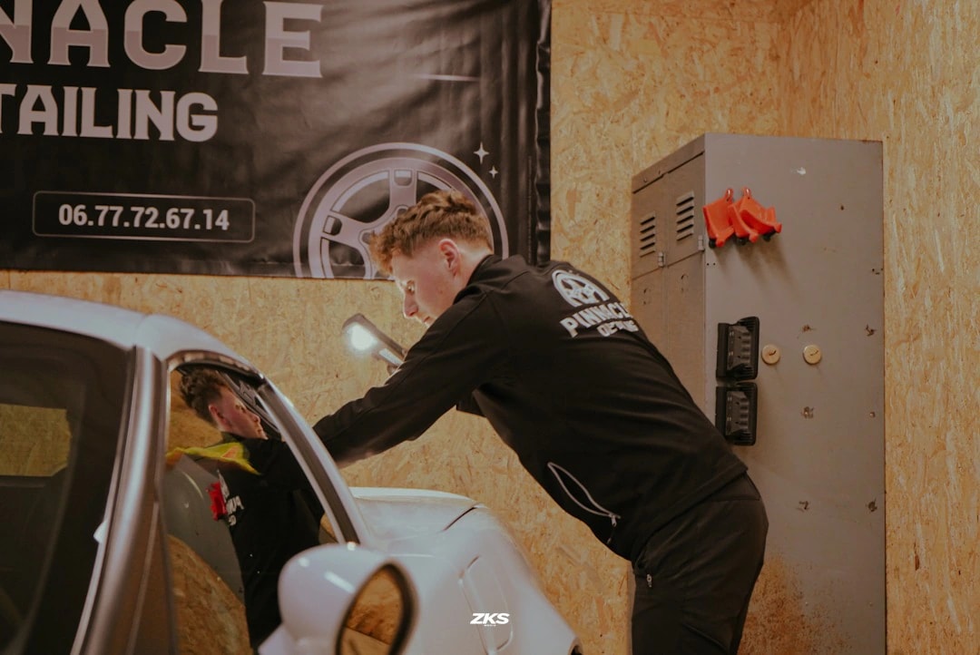Scotty au travail sur une voiture dans l’atelier, devant l’enseigne Pinnacle Detailing