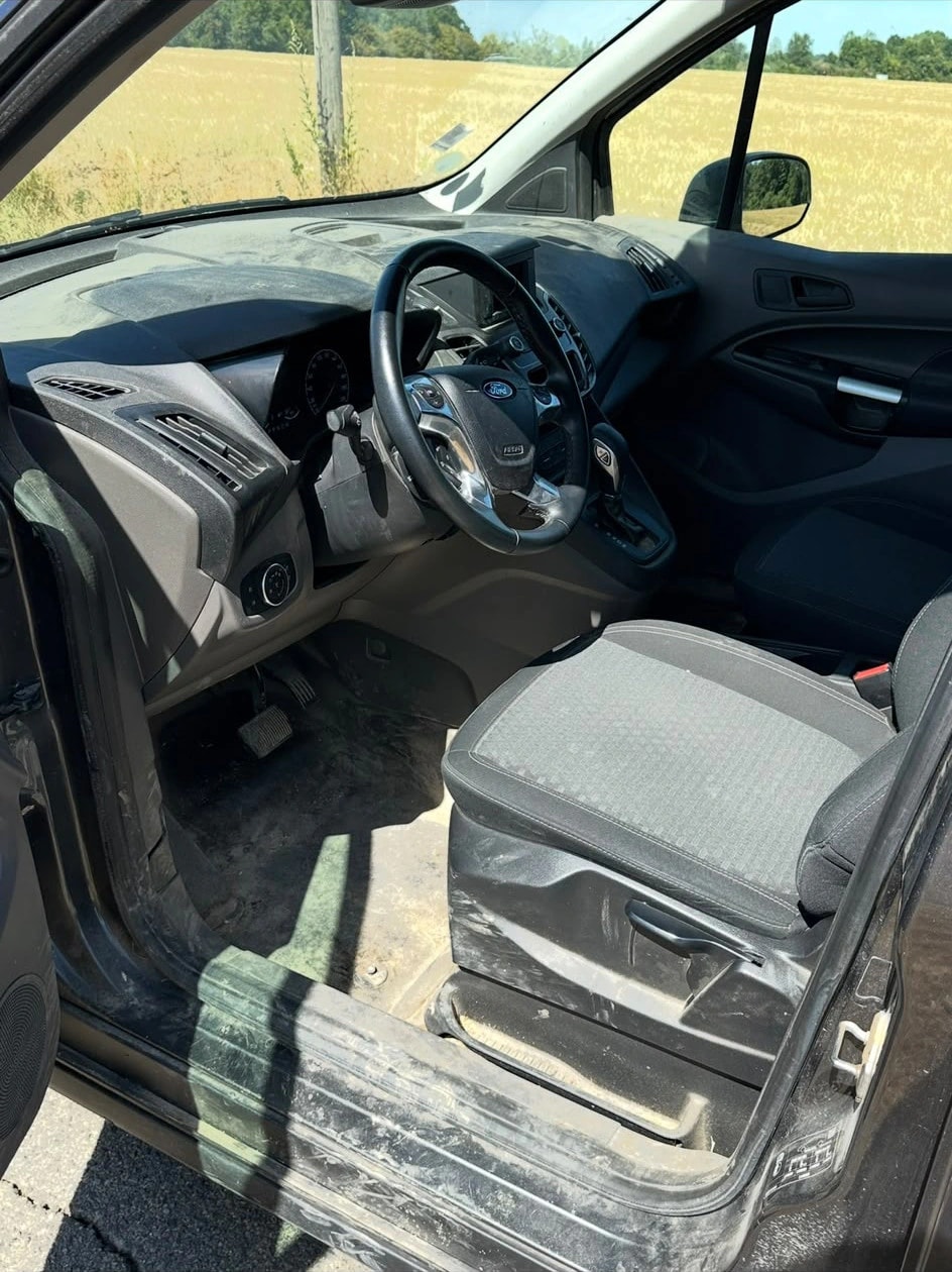 Avant : poste de conduite d’un Ford Transit Connect, sol et seuil couverts de terre